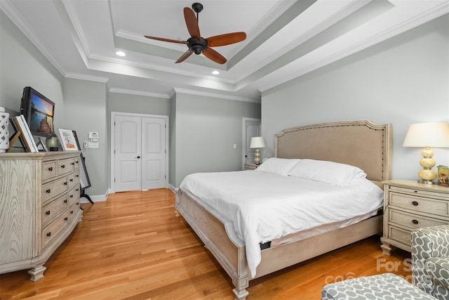 bedroom with crown molding, ceiling fan, light hardwood / wood-style floors, and a tray ceiling