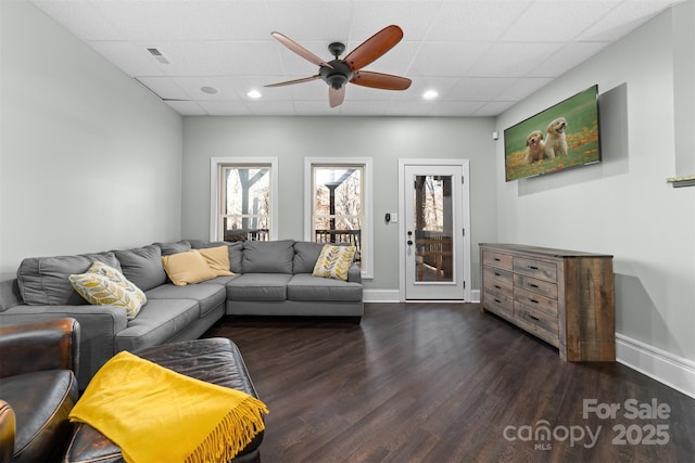 living room featuring dark hardwood / wood-style flooring, ceiling fan, and a drop ceiling