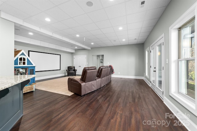 living room with dark hardwood / wood-style floors and a drop ceiling