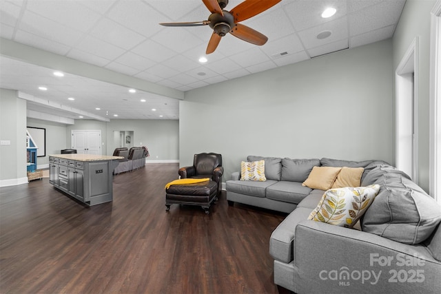 living room featuring ceiling fan, a drop ceiling, and dark hardwood / wood-style flooring