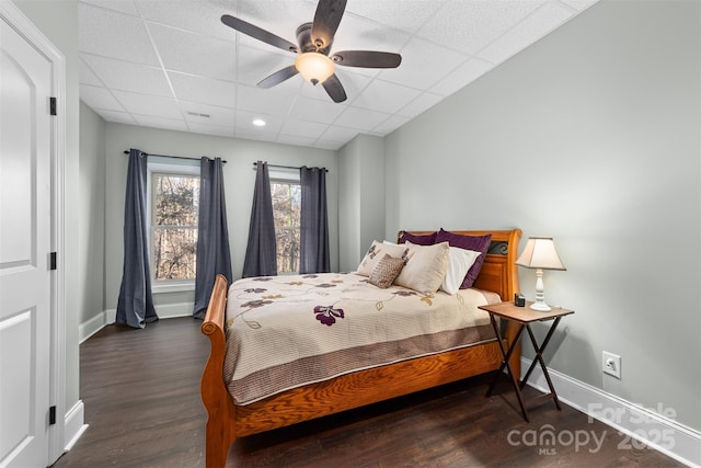 bedroom featuring a drop ceiling, dark hardwood / wood-style flooring, and ceiling fan