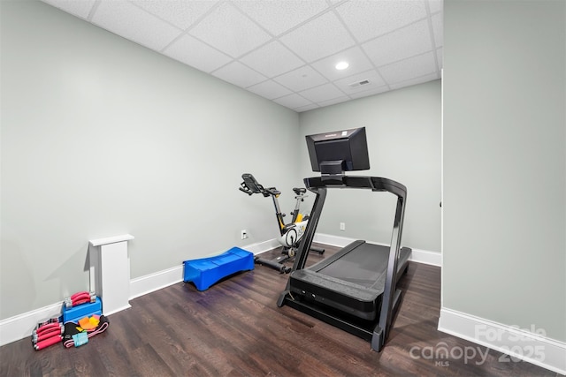 workout area featuring a drop ceiling and dark hardwood / wood-style flooring