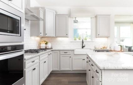 kitchen featuring tasteful backsplash, white cabinetry, sink, and stainless steel appliances