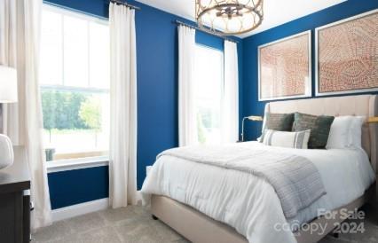 bedroom with multiple windows, light carpet, and a notable chandelier