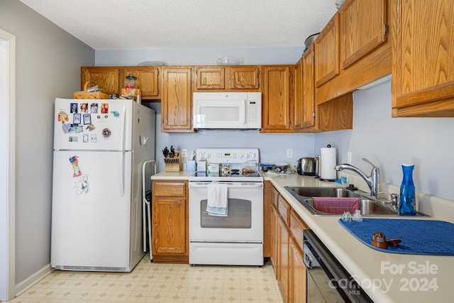 kitchen with a textured ceiling, white appliances, and sink