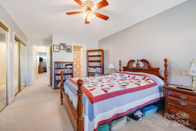 carpeted bedroom with a textured ceiling, ensuite bathroom, and ceiling fan