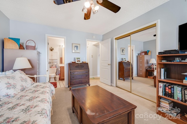 carpeted bedroom with ensuite bath, ceiling fan, a closet, and a textured ceiling