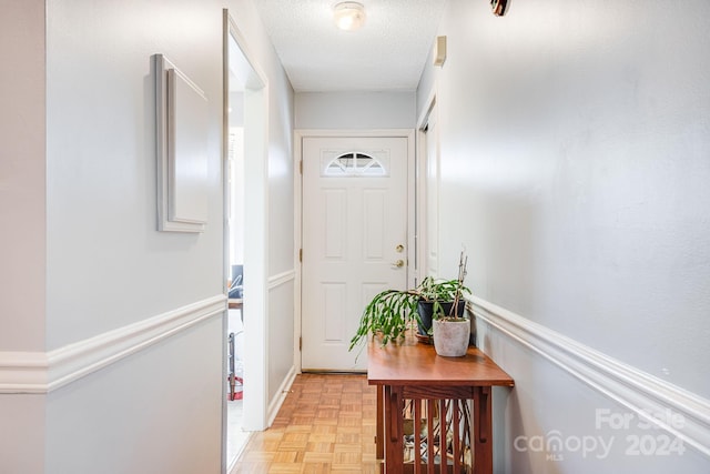 doorway featuring a textured ceiling and light parquet flooring