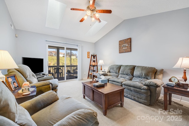 living room featuring ceiling fan, vaulted ceiling with skylight, and light carpet