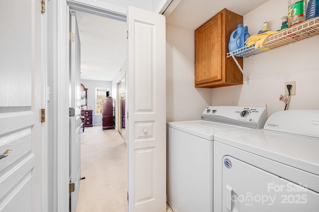 washroom featuring independent washer and dryer, light carpet, cabinets, and a textured ceiling