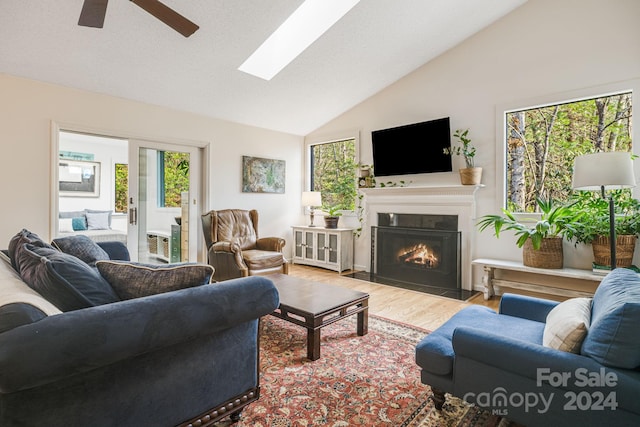 living room with a skylight, ceiling fan, plenty of natural light, and light hardwood / wood-style floors