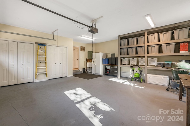 garage featuring white refrigerator with ice dispenser and a garage door opener