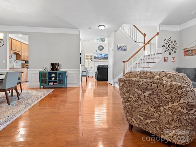 living room with sink, light hardwood / wood-style floors, and ornamental molding