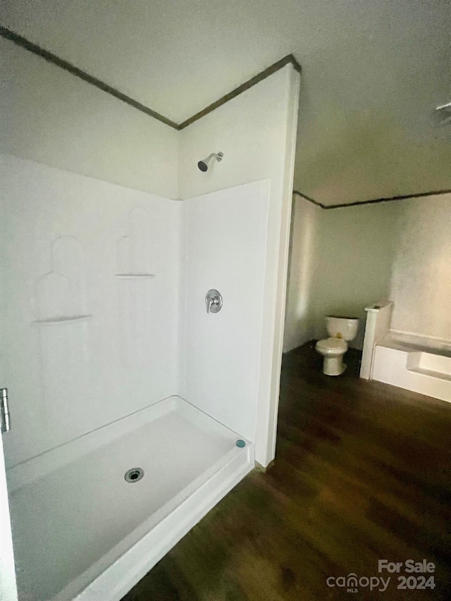 bathroom with a shower, toilet, and hardwood / wood-style flooring