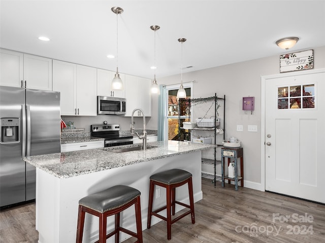 kitchen with a kitchen island with sink, dark wood-type flooring, white cabinets, and stainless steel appliances