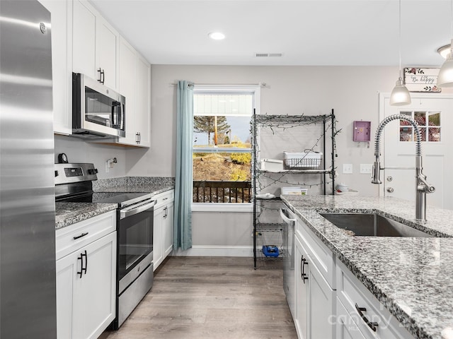 kitchen with visible vents, a sink, wood finished floors, appliances with stainless steel finishes, and white cabinets