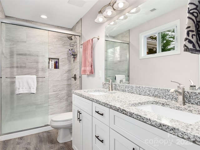 bathroom with a sink, toilet, a stall shower, and wood finished floors