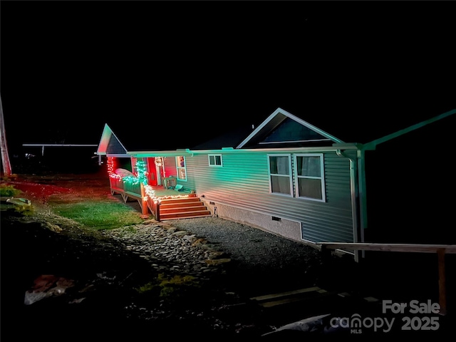 back of house at night featuring a deck