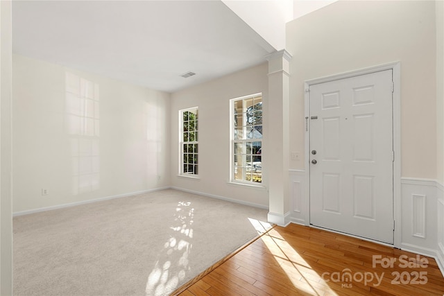 foyer with light hardwood / wood-style floors and ornate columns