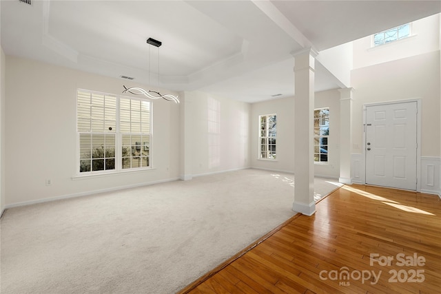 interior space featuring ornate columns, a raised ceiling, and carpet