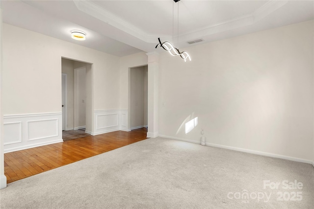 unfurnished dining area featuring a raised ceiling, crown molding, and carpet flooring