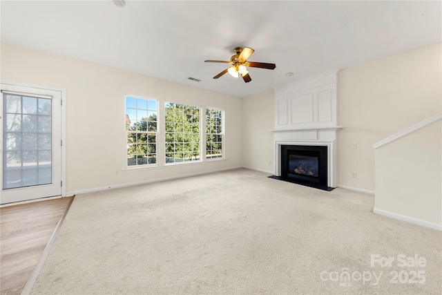 unfurnished living room featuring light carpet, a fireplace, and ceiling fan