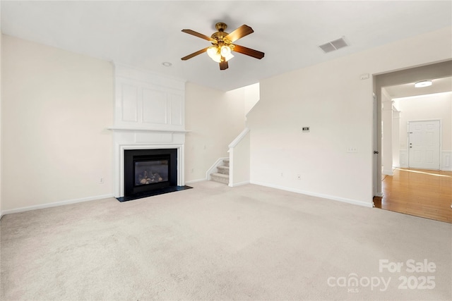 unfurnished living room featuring ceiling fan, light carpet, and a fireplace