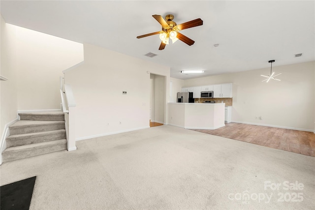 unfurnished living room with ceiling fan and light colored carpet