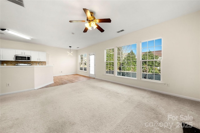 unfurnished living room with ceiling fan and light colored carpet