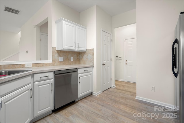 kitchen with stainless steel appliances, decorative backsplash, white cabinets, light hardwood / wood-style flooring, and sink