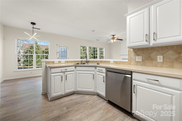 kitchen with kitchen peninsula, sink, white cabinetry, decorative light fixtures, and stainless steel dishwasher