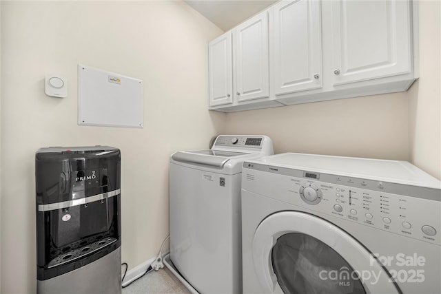 clothes washing area featuring separate washer and dryer and cabinets