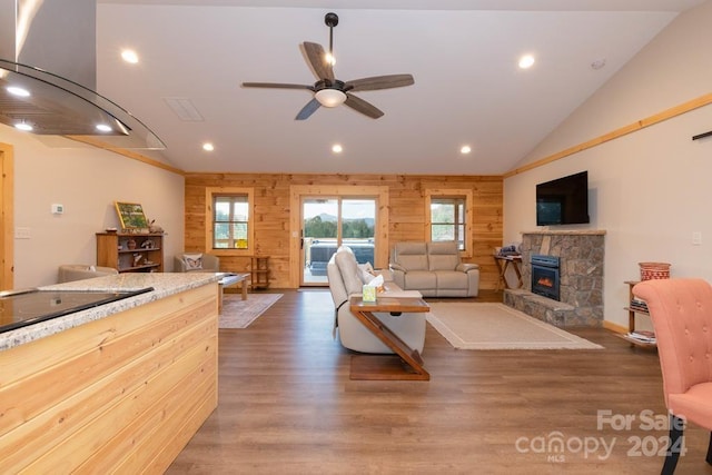 living room with ceiling fan, wood walls, dark wood-type flooring, and lofted ceiling