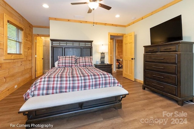 bedroom with ceiling fan, light hardwood / wood-style floors, ornamental molding, and wooden walls