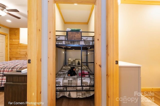 bedroom featuring ceiling fan, hardwood / wood-style floors, crown molding, and wooden walls