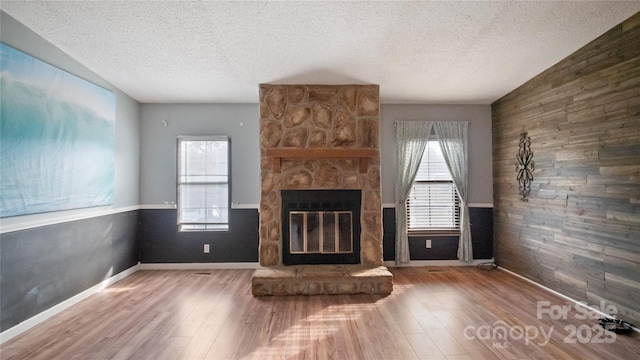 unfurnished living room with a fireplace, wood-type flooring, and a textured ceiling