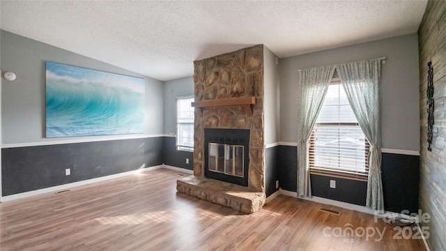 unfurnished living room featuring a fireplace, a healthy amount of sunlight, vaulted ceiling, and hardwood / wood-style flooring