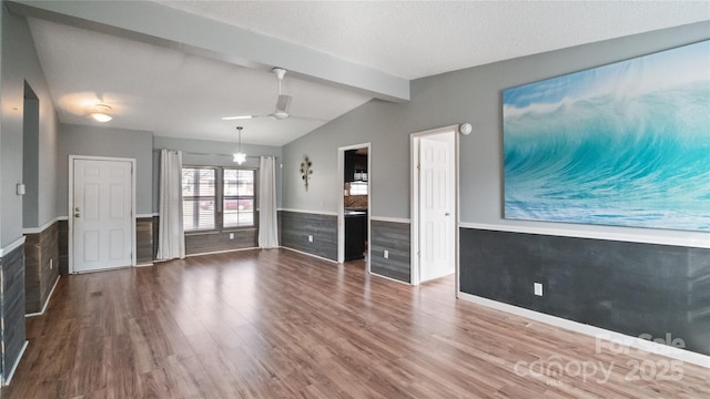 unfurnished living room featuring a textured ceiling, lofted ceiling with beams, hardwood / wood-style flooring, and ceiling fan