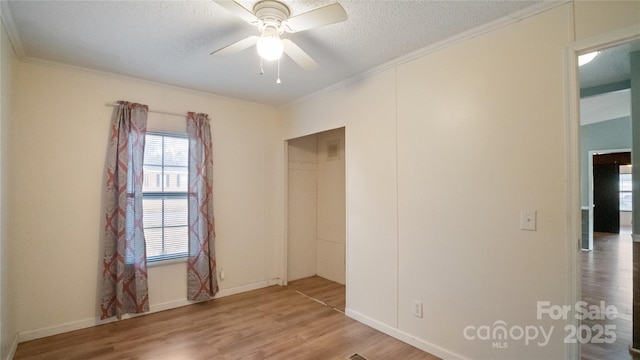 spare room with hardwood / wood-style flooring, ceiling fan, crown molding, and a textured ceiling