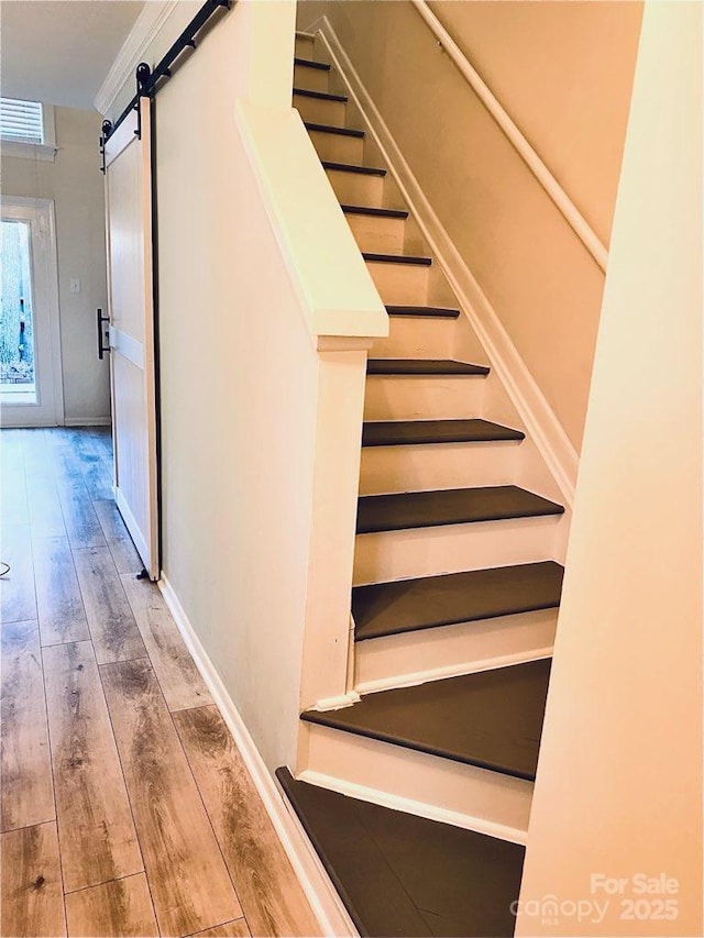 stairs featuring hardwood / wood-style flooring, ornamental molding, and a barn door