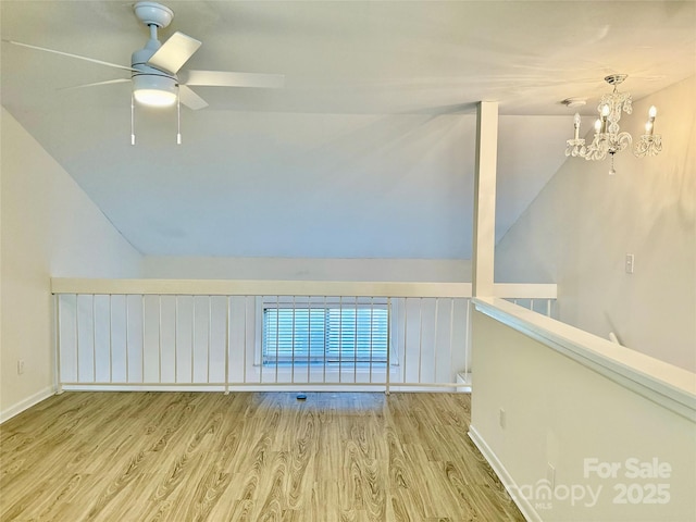 unfurnished room featuring ceiling fan with notable chandelier, lofted ceiling, and light wood-type flooring