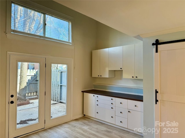 kitchen with a barn door, white cabinetry, and light hardwood / wood-style floors