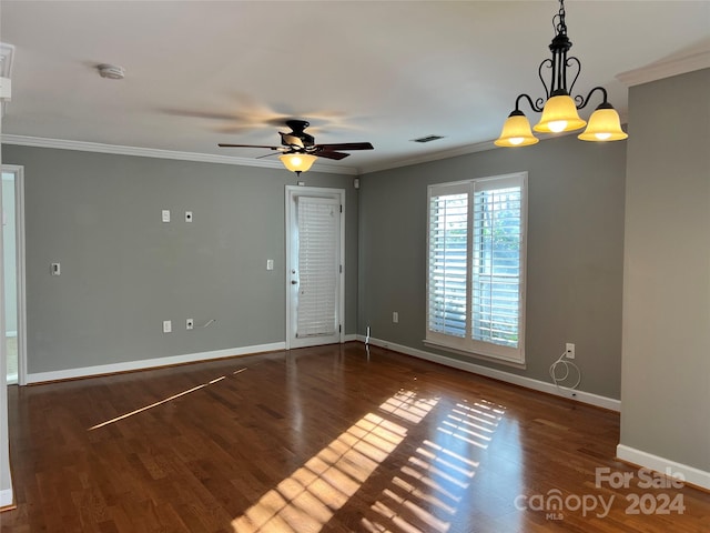 empty room with dark hardwood / wood-style floors, ornamental molding, and ceiling fan with notable chandelier