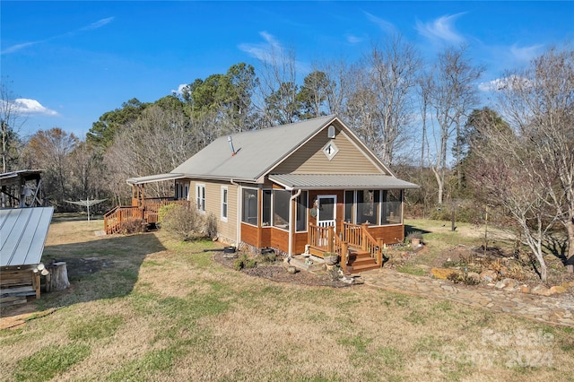 rear view of property with a sunroom and a lawn