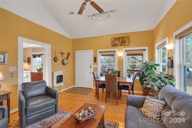 living room featuring hardwood / wood-style floors, heating unit, vaulted ceiling, and plenty of natural light