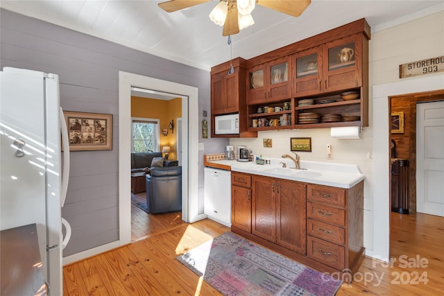 kitchen with ceiling fan, sink, light hardwood / wood-style flooring, white appliances, and wooden walls