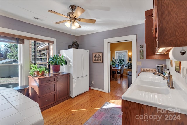 kitchen with ceiling fan, sink, light hardwood / wood-style flooring, white fridge, and wooden walls