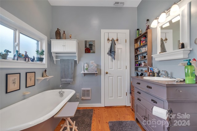 bathroom with hardwood / wood-style floors, vanity, heating unit, and a tub