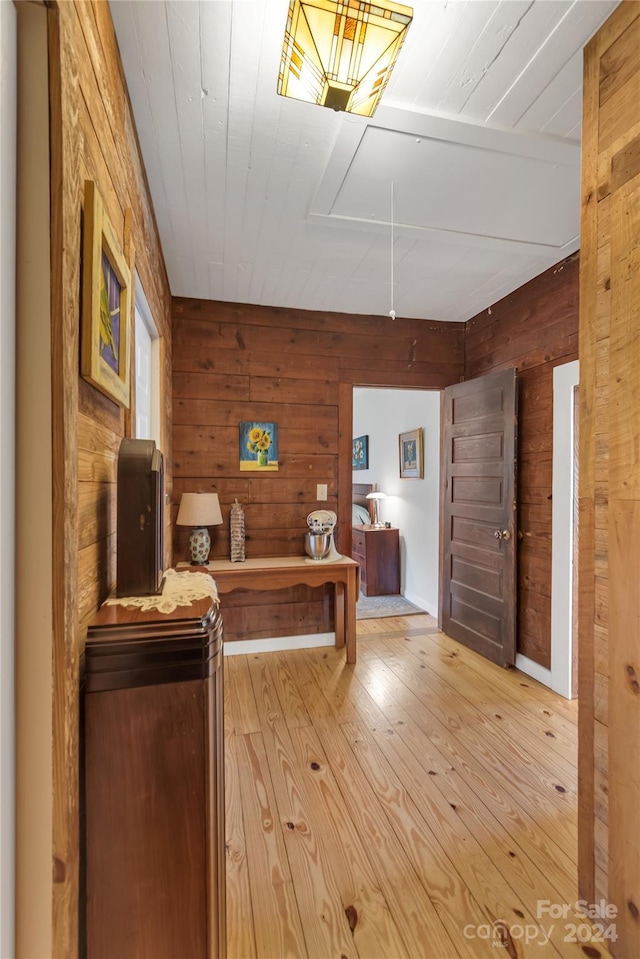 interior space with light hardwood / wood-style floors and wooden walls