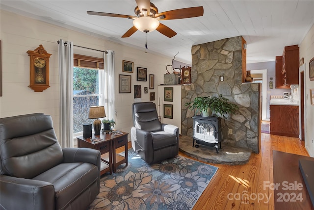 living room featuring a wood stove, ceiling fan, and hardwood / wood-style floors